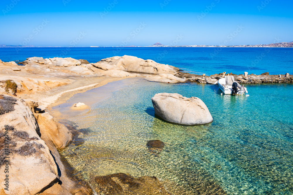 Rocks and stones on idyllic sandy beach of Orkos bay and calm crystal clear azure sea water, Naxos island, Cyclades, Greece