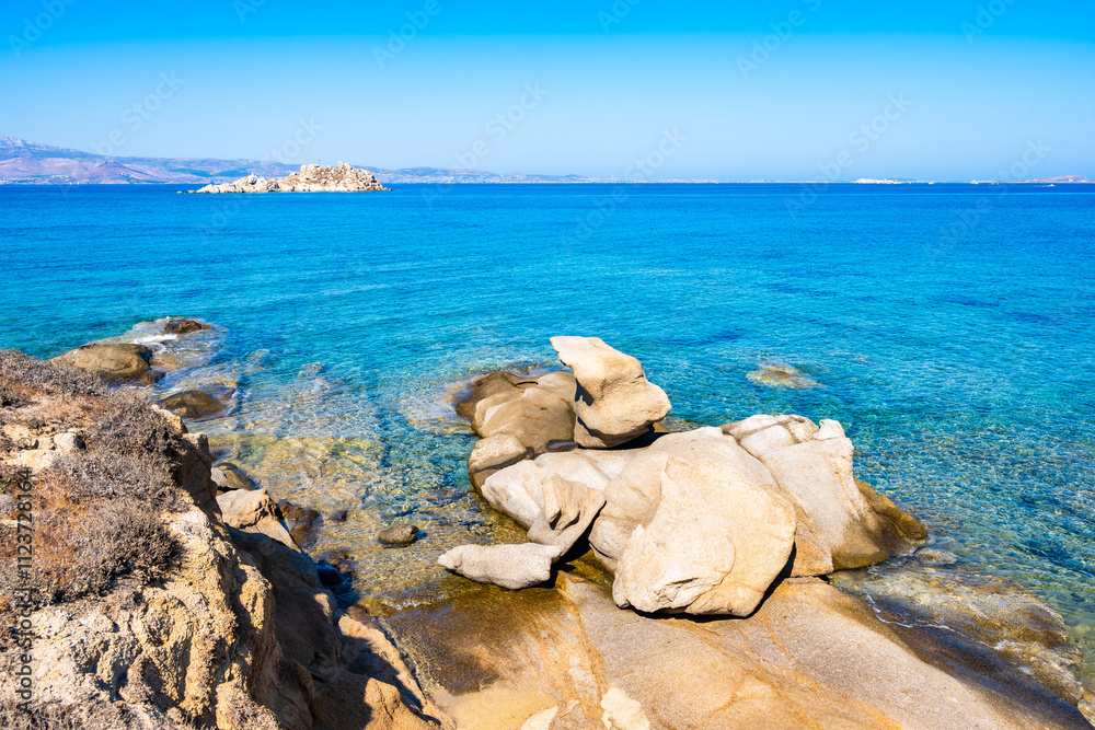 Rocks and stones on idyllic sandy beach of Orkos bay and calm crystal clear azure sea water, Naxos island, Cyclades, Greece