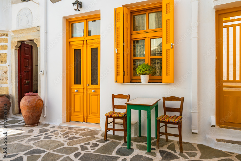 Yellow chairs, doors and windows on small square in historic old part of Chora village, Naxos island, Cyclades, Greece