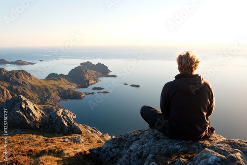 Mountaineer enjoys tranquil sunset view over serene coastal waters at remote rocky landscape in the evening