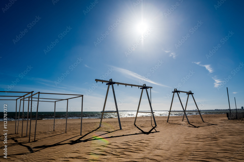 Fototapeta premium Plage vide avec des jeux d'enfants, sous un soleil d'hiver, en hors saison