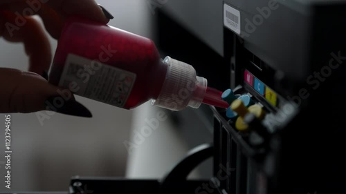 Close-up of technician female carefully filling printer cartridge with magenta ink, demonstrating process of maintaining and refilling ink cartridges in contemporary printing device, slow motion.