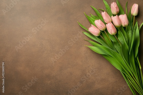   Un ramo de tulipanes rosados frescos con hojas verdes, colocado sobre un fondo marrón cálido y minimalista.
 photo