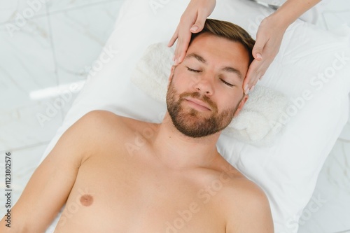 Handsome middle-aged man enjoying relaxing spa massage with oils photo