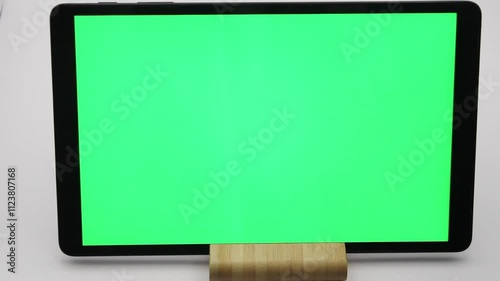 Displaying blank green screen on tablet positioned on wooden stand