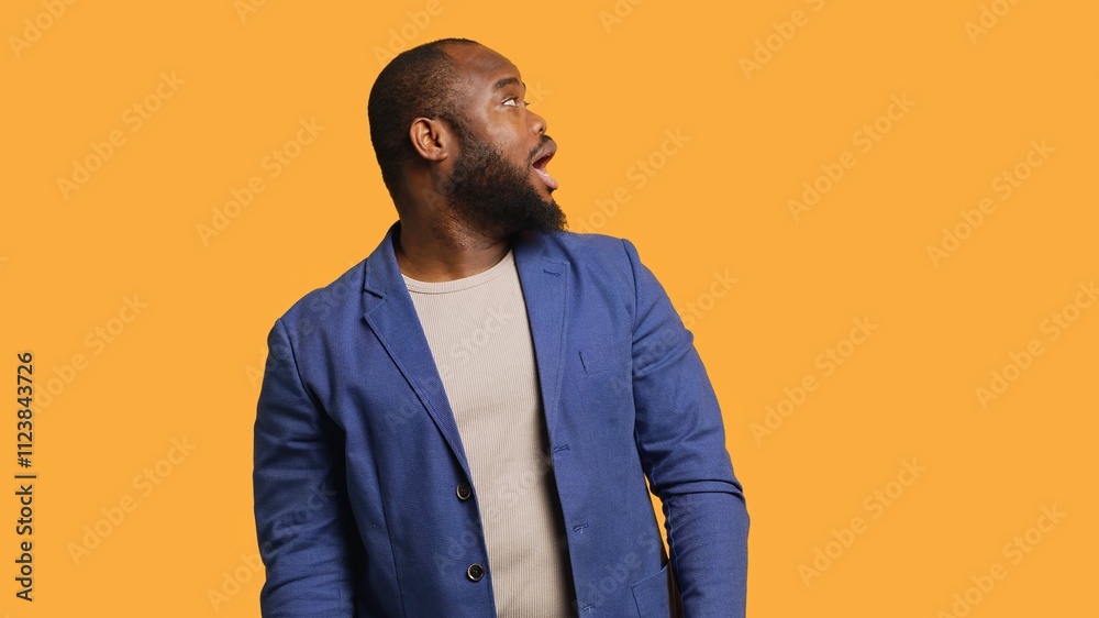Fototapeta premium Smiling man having friendly conversation with friend sitting off camera, isolated over studio background. BIPOC person having fun catching up with mate, having lively discussion, camera A
