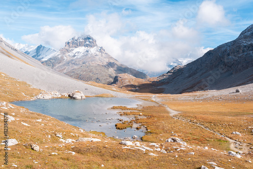 Clear blue mountain lake under clouds and a blue sky, with mountains in the background, called the Long Lake, in the Vanoise Massif, Savoie department, in the French Alps, France. photo