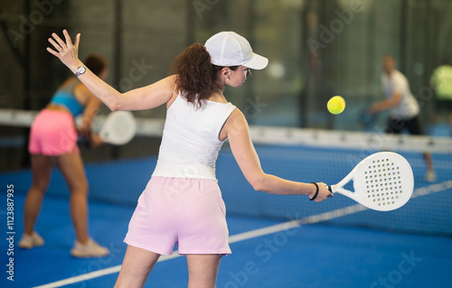 Sporty woman playing padel on open court on summer day. Sport and active lifestyle concept photo