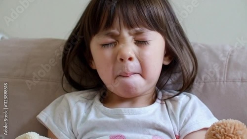 A sleepy little girl yawning and stretching in her cozy pajamas, cuddling a soft stuffed animal