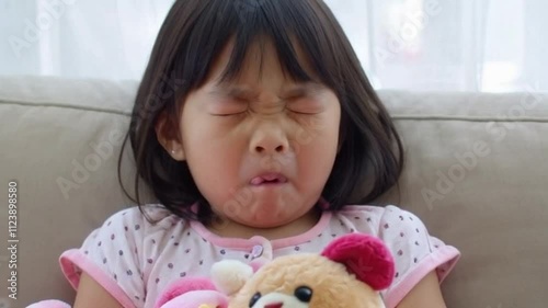 A sleepy little girl yawning and stretching in her cozy pajamas, cuddling a soft stuffed animal