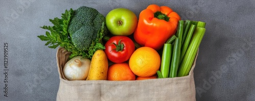 A vibrant assortment of fresh vegetables and fruits in a reusable fabric bag. photo