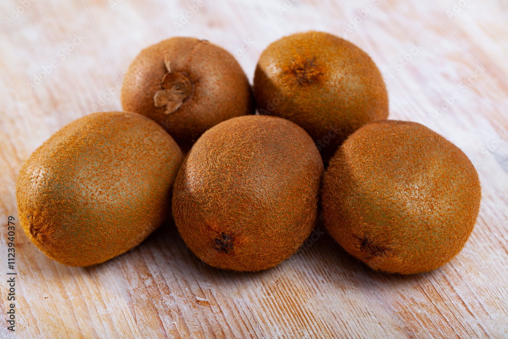 Fototapeta premium Pile of fresh unpeeled kiwifruits on wooden background. Concept of health benefits of fruits