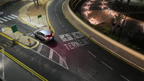 Cars driving through the lane dedicated to taxi and coach vehicles to approach the Malta Airport terminal building at night. photo