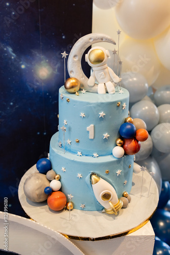 Fototapeta Naklejka Na Ścianę i Meble -  blue space themed birthday cake with astronaut and rocket decoration for baby's first birthday 