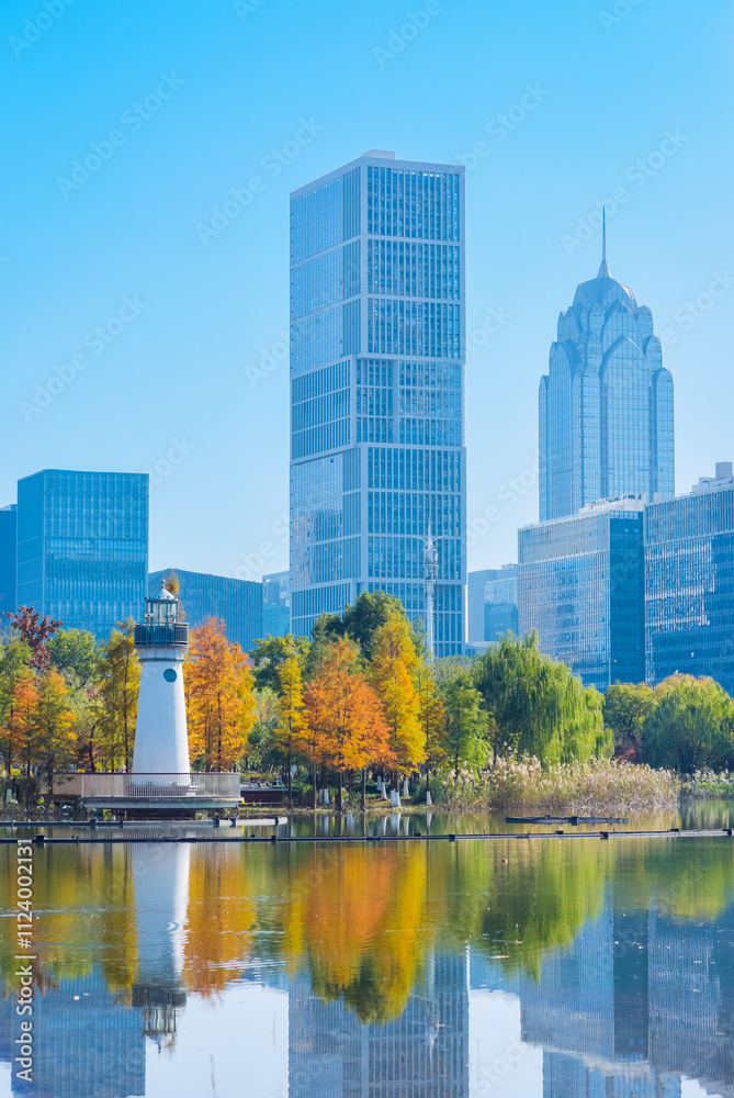 Fototapeta premium Beautiful landscape of golden autumn season at Yinzhou Park, with background of modern buildings of Southern Business District (Ningbo CBD) in Ningbo, Ningbo, Zhejiang, China