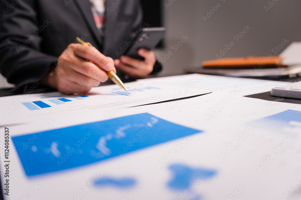 A young Asian man in a formal suit works late at night at his desk, analyzing stock market charts on a laptop and tablet, ensuring accuracy in financial data analysis. A young Asian man in a formal suit works late at night at his desk, analyzing stock market charts on a laptop and tablet, ensuring accuracy in financial data analysis.