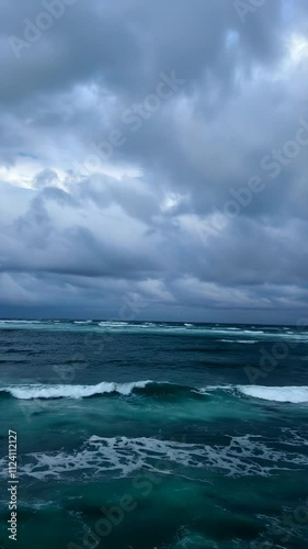 vertical video of blue tranquil sea with waves and cloudy sky