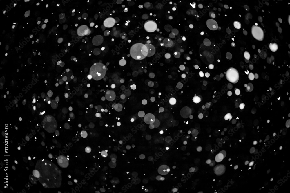 Bokeh lights on black background, shot of flying snowflakes in the air Bokeh lights on black background, shot of flying snowflakes in the air