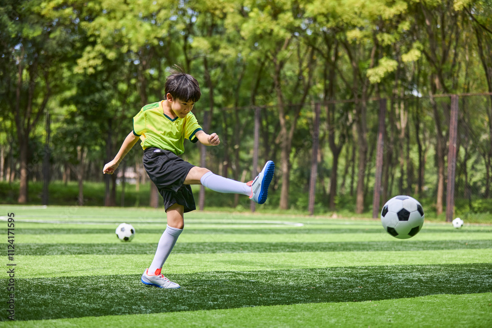 Chinese Boy Playing Football on Soccer Field Chinese Boy Playing Football on Soccer Field