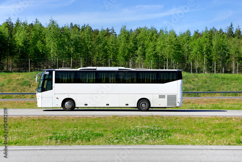 White coach bus at speed on motorway on a sunny day of summer, side view, copy space for your text.