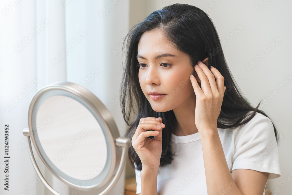 Anti aging beauty, happy asian young woman looking in mirror reflection at home, touching face skin satisfied with healthy moisturized, skin care treatment cosmetic for dry skin during morning routine Anti aging beauty, happy asian young woman looking in mirror reflection at home, touching face skin satisfied with healthy moisturized, skin care treatment cosmetic for dry skin during morning routine
