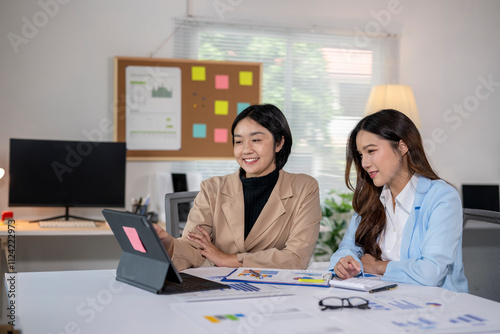 Two young businesswomen working together using laptop computer in office