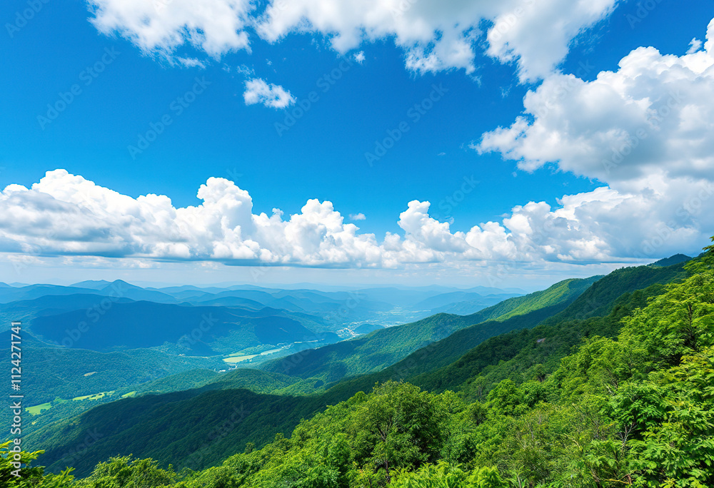 A scenic view of a mountainous landscape with lush green forests and rolling hills under a blue sky with fluffy white clouds
