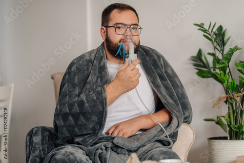 Sick man using nebulizer for asthma treatment at home