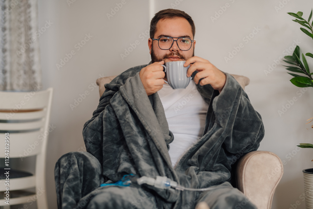 Sick man drinking hot beverage at home with nebulizer Sick man drinking hot beverage at home with nebulizer