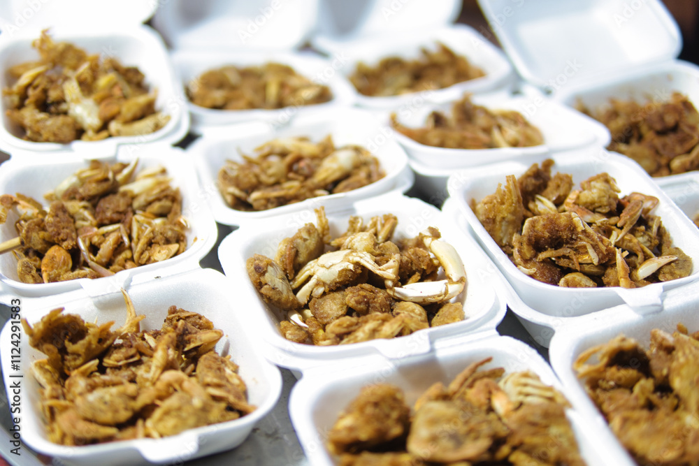 Many small white containers hold fried crab pieces. Many small white containers hold fried crab pieces.