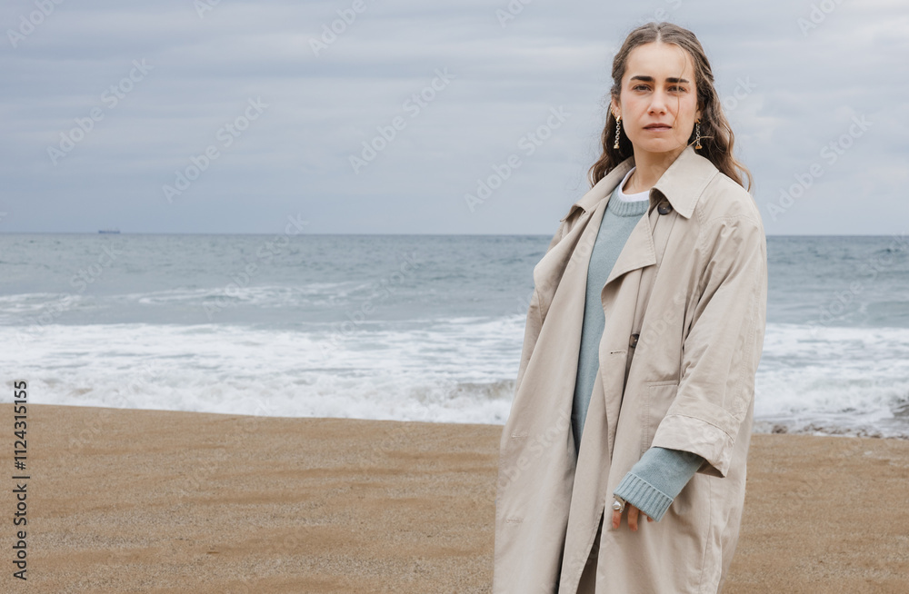Portrait of a young woman by the ocean wearing a trench coat Portrait of a young woman by the ocean wearing a trench coat