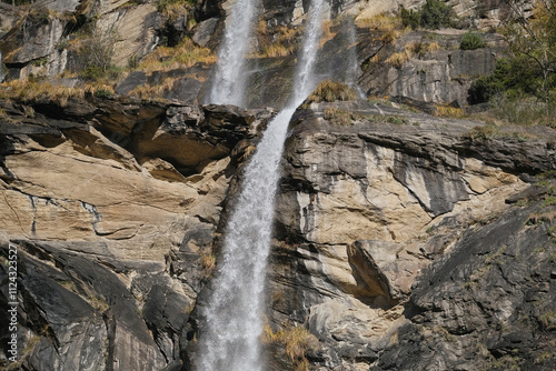 Fototapeta Naklejka Na Ścianę i Meble -  Cascading waterfall with mossy rocks in an alpine park, with clean, fresh water and lush foliage. Perfect for outdoor travel and nature backgrounds.