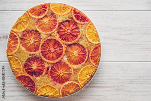 Delisious freshly baked homemade blood orange upside-down cake on white wooden background, top down view. Popular winter holiday dessert. Copy space for text.