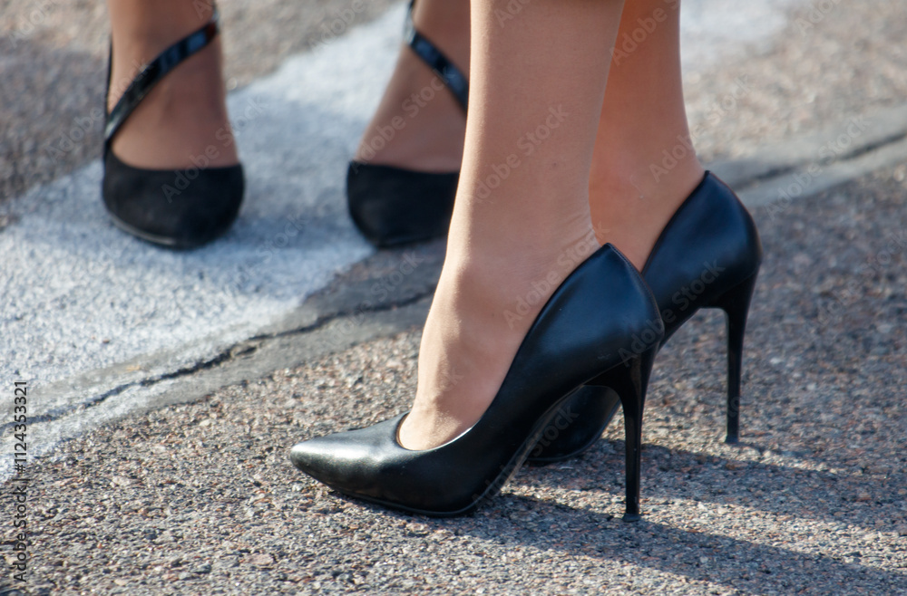 Two women wearing black high heels are standing next to each other Two women wearing black high heels are standing next to each other