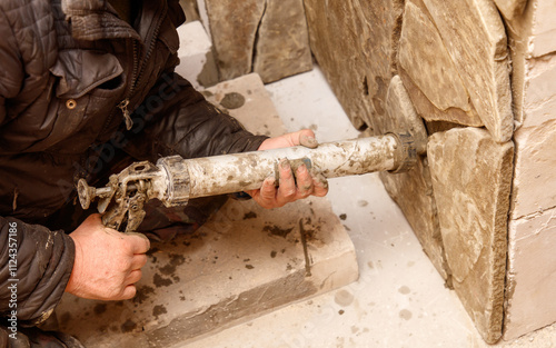 A man is working on a wall, using a caulking gun to fill in cracks photo