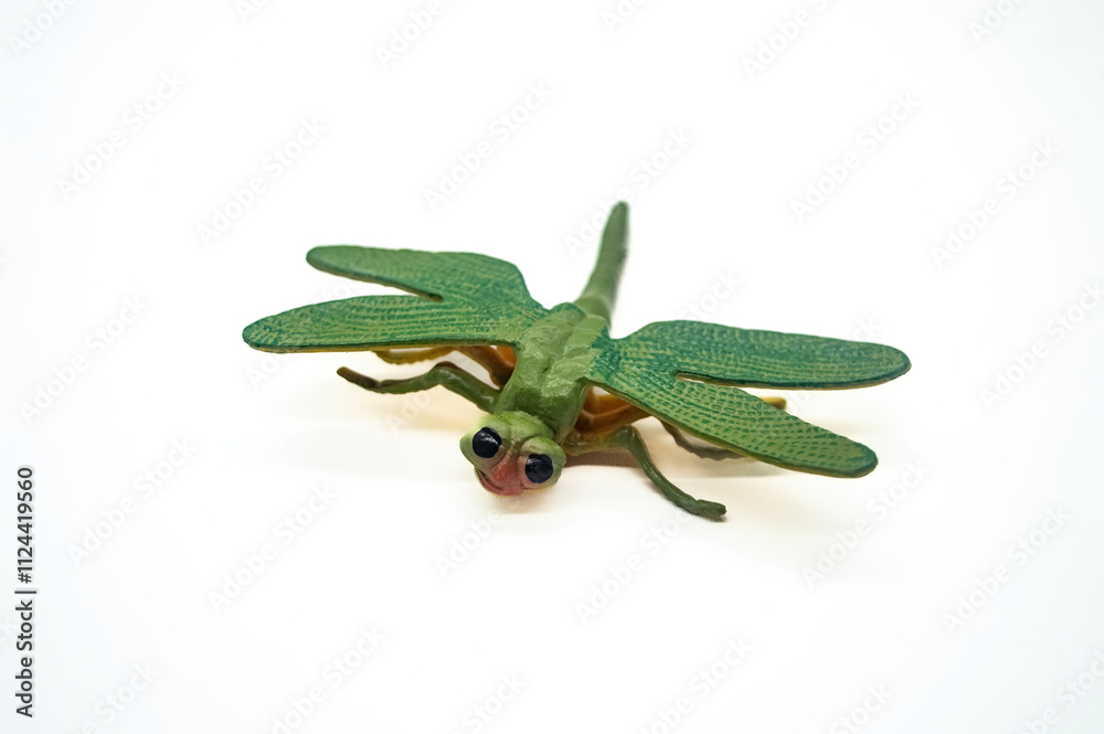 Obraz premium Green dragonfly toy isolated on white background, showcasing detailed wings and body texture. Perfect for educational purposes or insect themed decorations