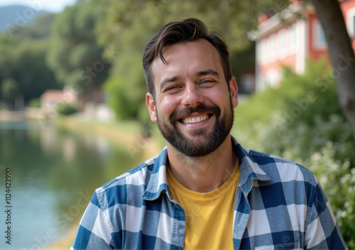 Man with beard and plaid shirt smiling near water