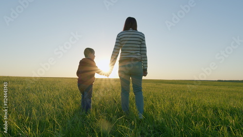 Young Mother Go With Son On Field In Evening. Happy Family Together. Family Mothers Day Funny On Nature. Mom And Son Of Five Years Old Walk In Field Or Park At Sunset. Gimbal Stabilize.