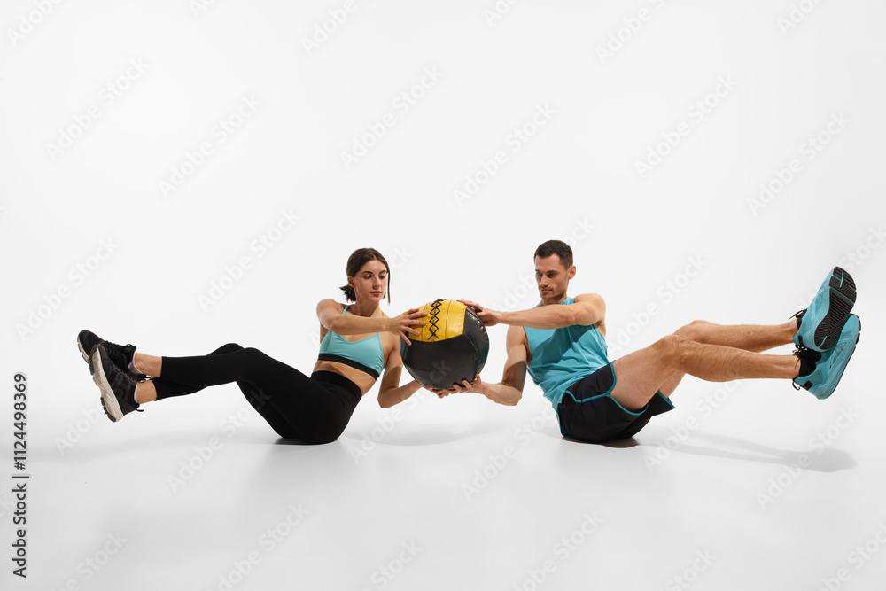 Obraz premium Intensive training. Young athletic man and slim woman training with medicine ball against white studio background. Strong body. Concept of sport, active and healthy lifestyle, workout, fitness