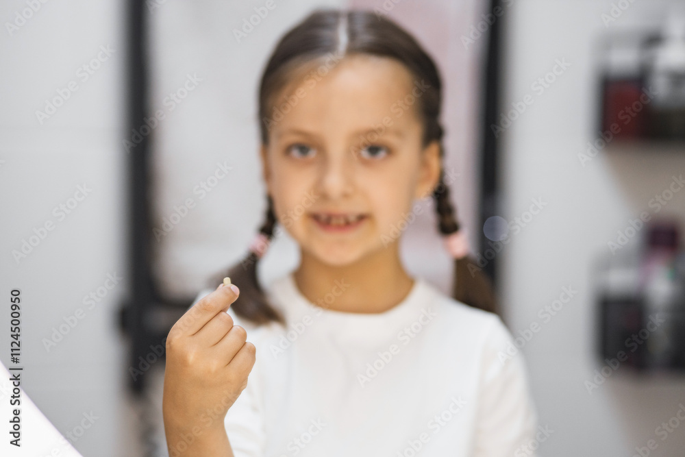 Portrait of young Caucasian girl displaying freshly lost tooth with delight in bathroom. Symbolizes childhood milestones, growth, and personal achievement. Portrait of young Caucasian girl displaying freshly lost tooth with delight in bathroom. Symbolizes childhood milestones, growth, and personal achievement.