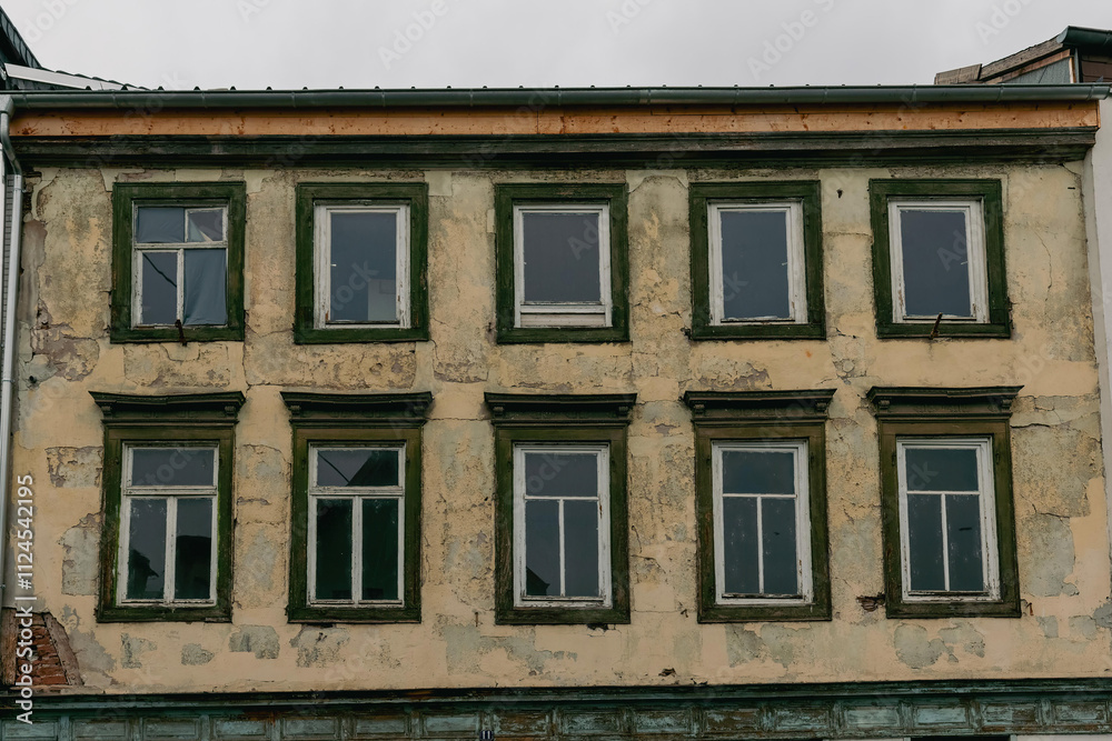Old building facade with weathered paint and multiple windows in a historic city Old building facade with weathered paint and multiple windows in a historic city