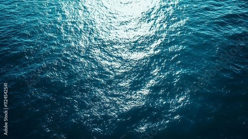 A deep blue ocean with light filtering through the water and soft waves, large empty space above for text or artwork photo