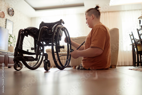 Boy with disability fixing wheelchair at home photo