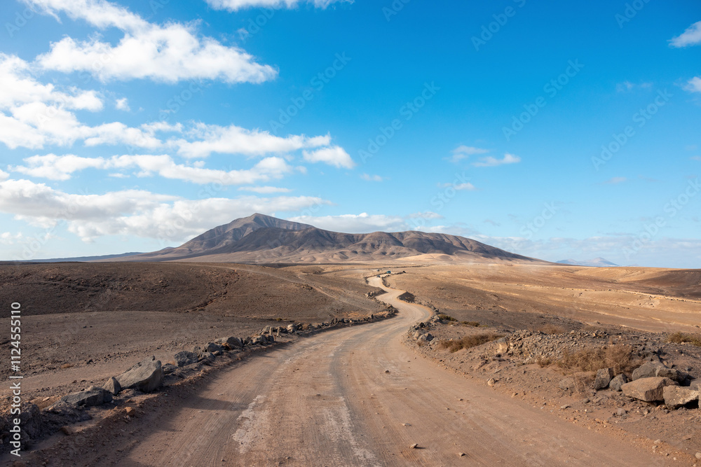 Winding gravel road in Lanzarote, Spain, through a remote desert landscape under a blue sky. Winding gravel road in Lanzarote, Spain, through a remote desert landscape under a blue sky.