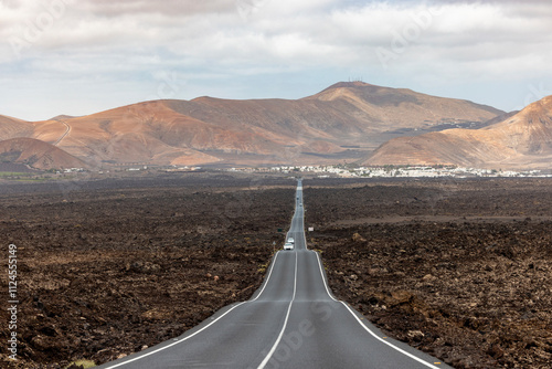 View of an endless straight road in Lanzarote, Yaiza, Spain, featuring the volcanic landscape of Timanfaya. photo