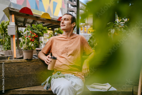 Mid adult man relaxing and drinking coffee in an urban garden.