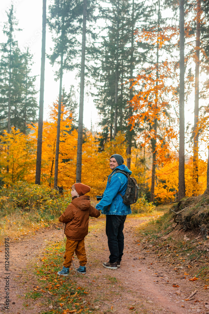 Man holding hand of son and exploring forest in autumn season Man holding hand of son and exploring forest in autumn season