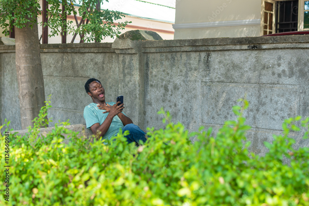 African American man siting in a garden using phone. African American man siting in a garden using phone.