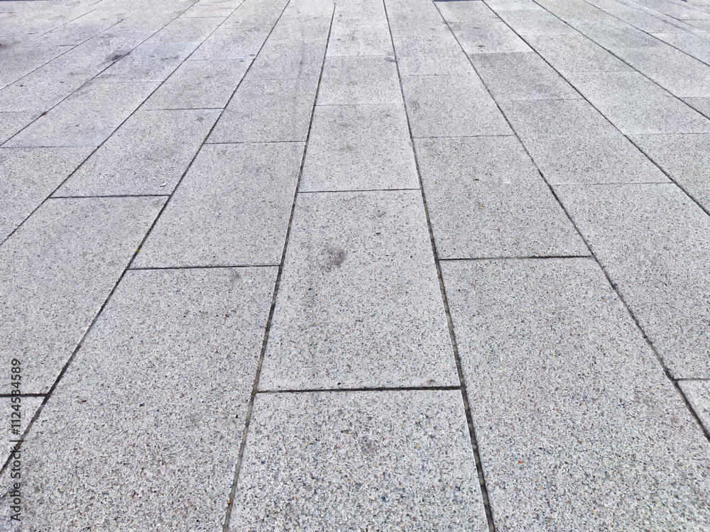 Fototapeta premium A clean, gray concrete surface featuring rectangular tiles arranged in a neat pattern under bright daylight