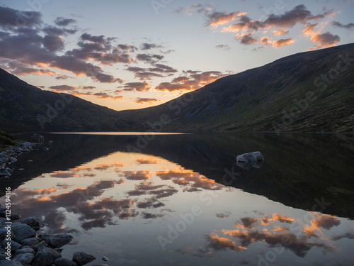 Remote mountain lake in Scotland reflecting clouds at dusk photo